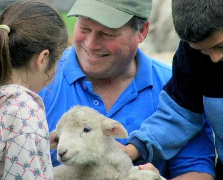 Children gathering around a lamb with a Fields of the Fatherless leader