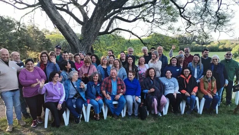A large retreat group gathered beneath a tree